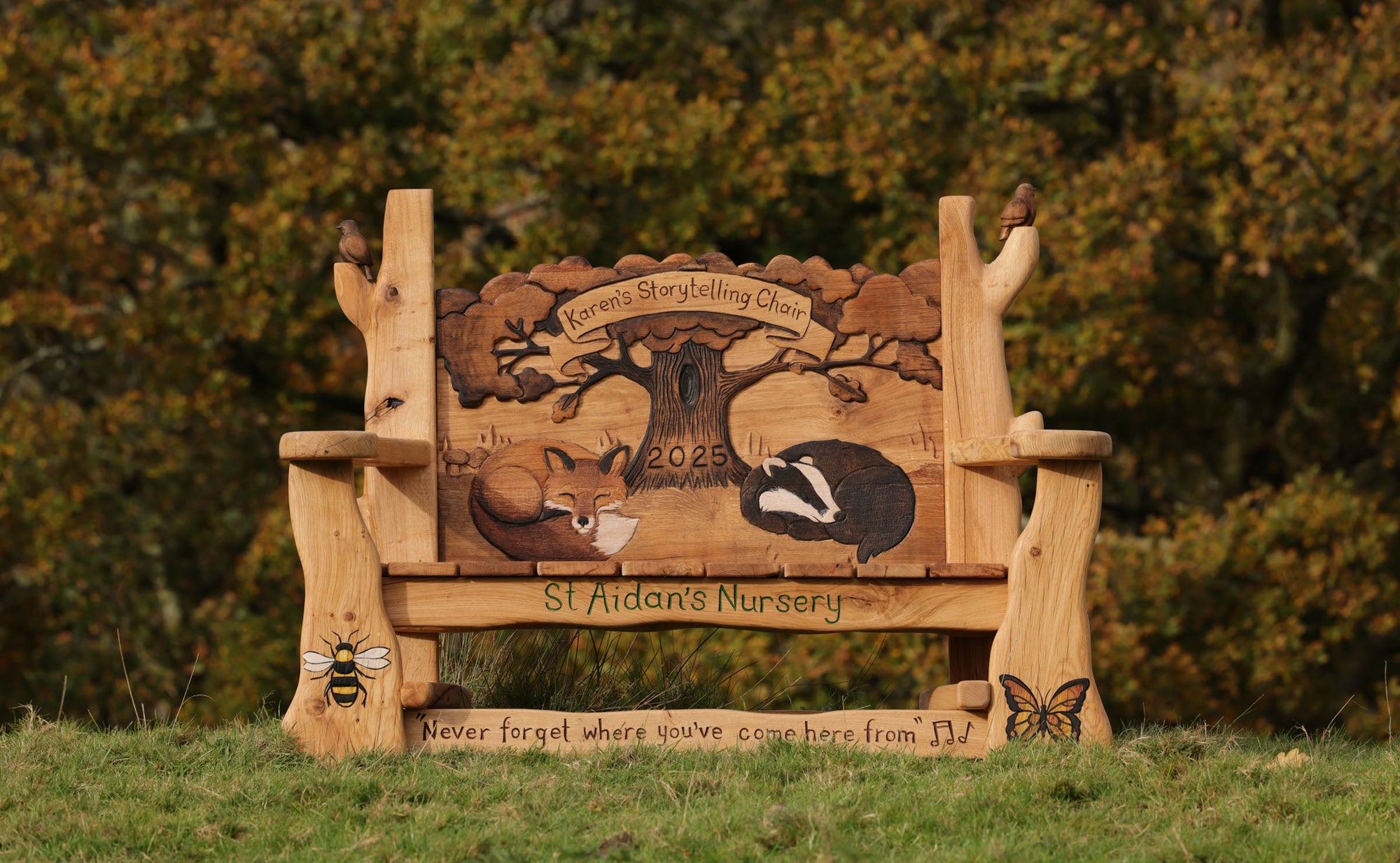 Wooden bench with engraved designs of animals and text, set against a natural background.
