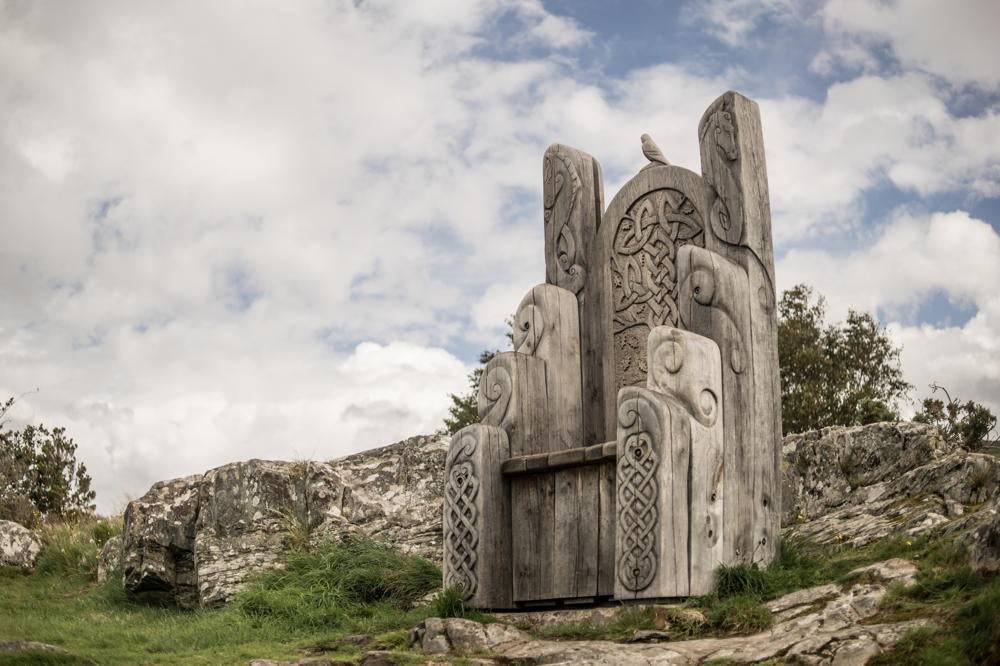 Carved oak throne chair by Harlech Castle wall — handmade giant Welsh throne