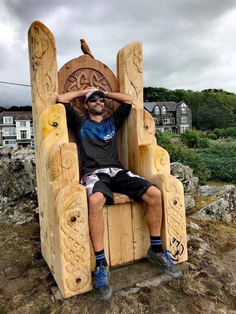 Craftsman beside carved giant Welsh oak throne — handmade statement furniture, Wales