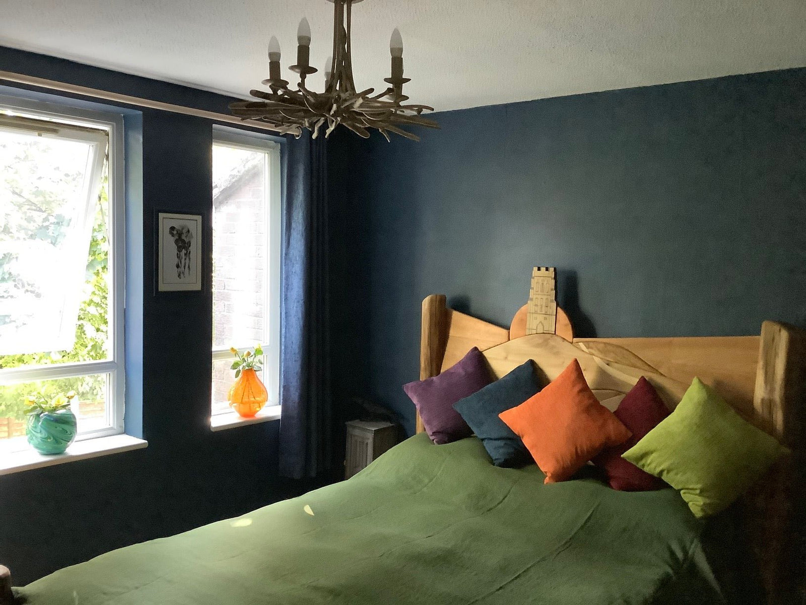 Handcrafted Glastonbury Tor sunrise bed in client's bedroom — bespoke carved oak bed, Wales