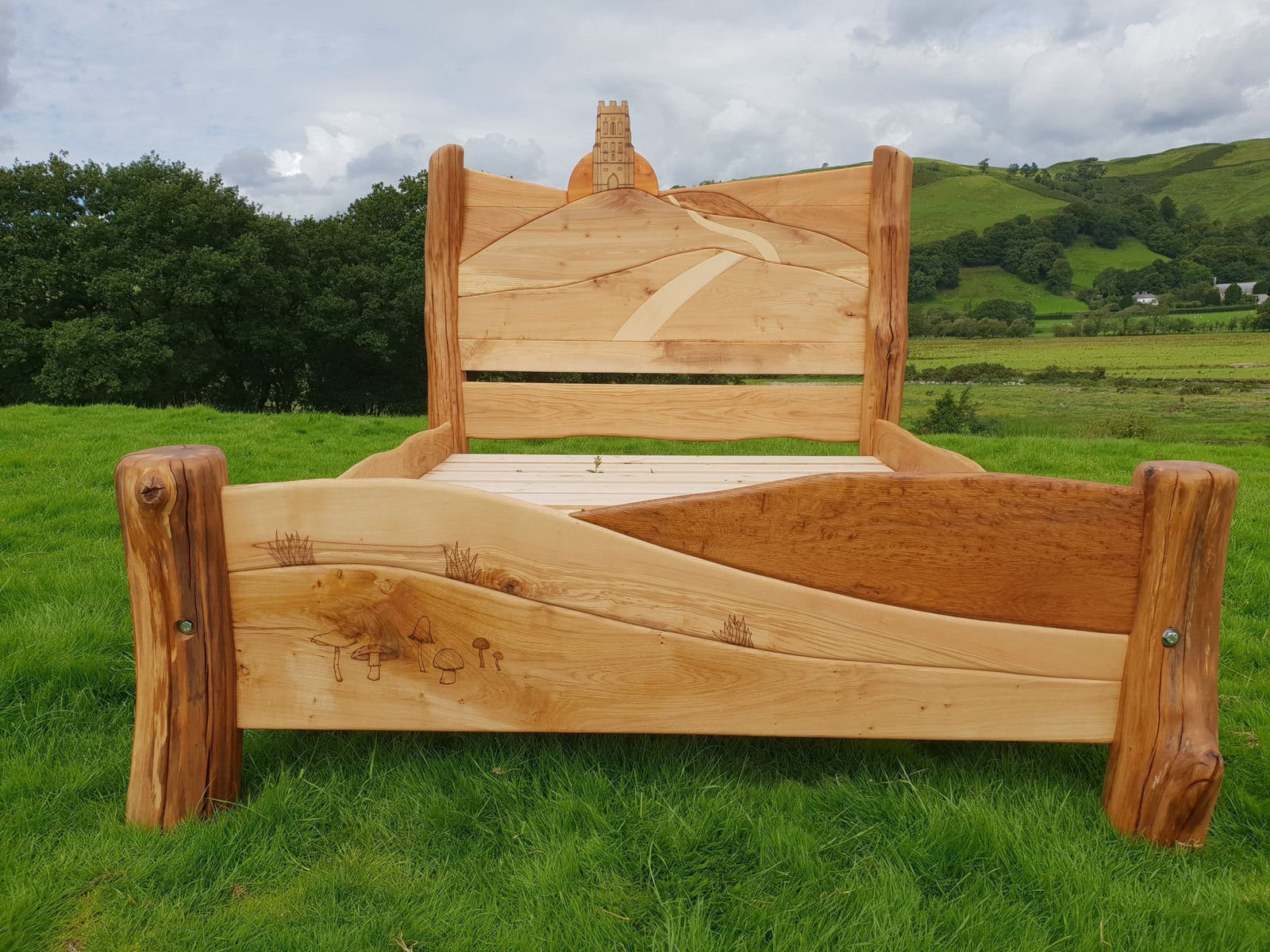 Glastonbury Tor carved bed with sunrise path design — handmade bespoke oak bedroom furniture, Wales
