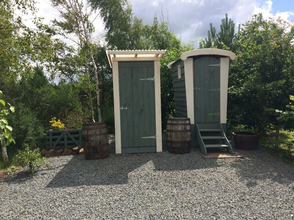Two compost toilets in garden setting with painted wooden steps