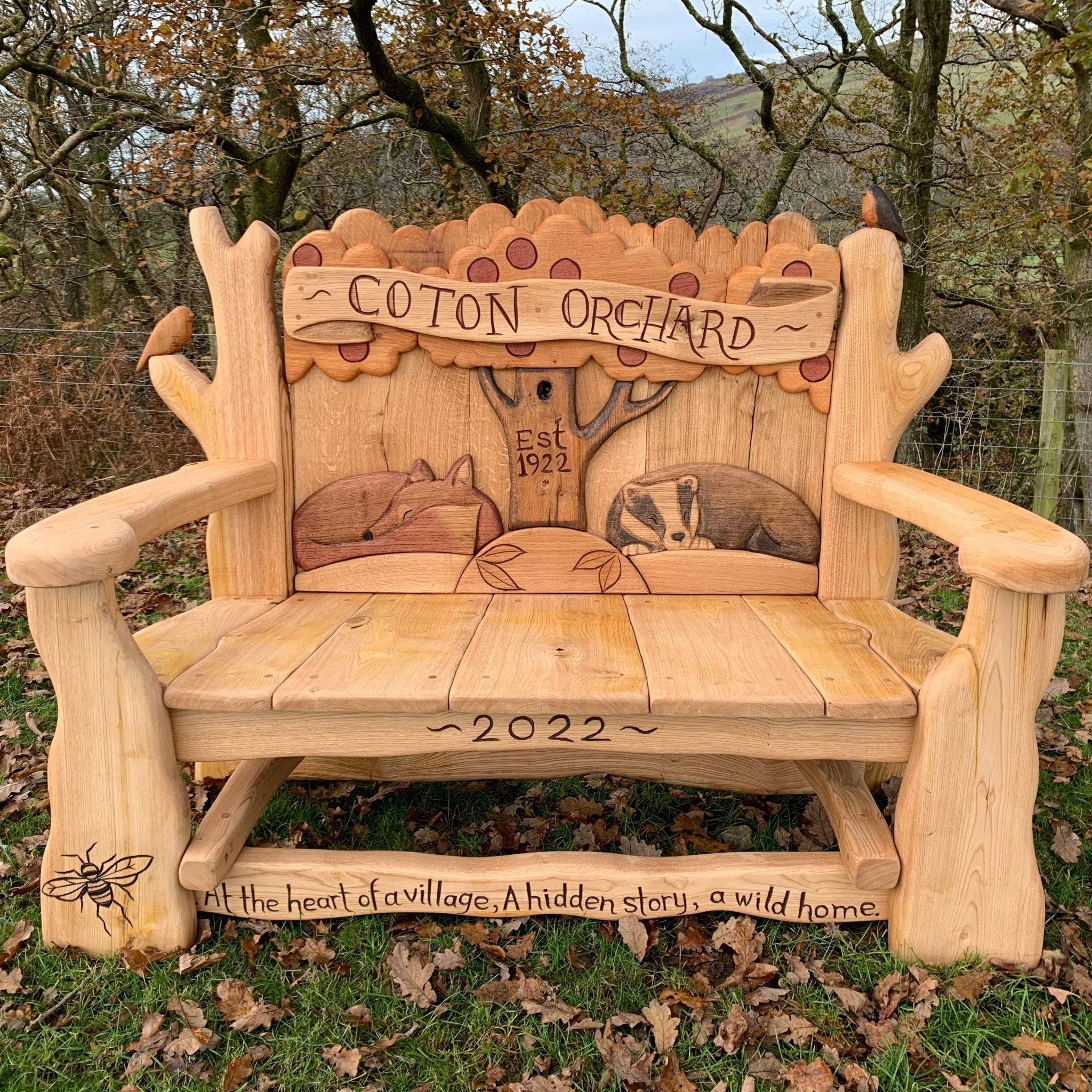 Handcrafted Coton Orchard Bench featuring wildlife carvings and a rustic design, celebrating heritage and nature.

