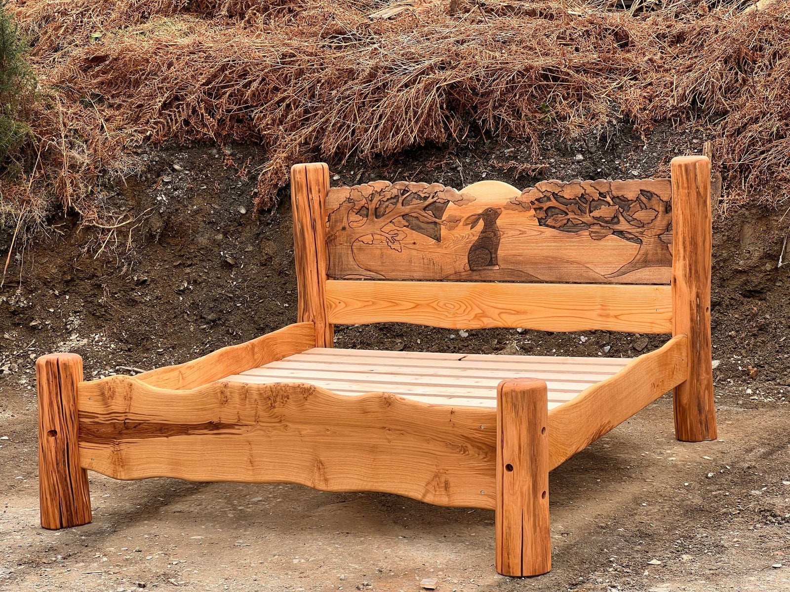 Handmade solid oak bed with hare carvings in natural outdoor setting — bespoke, Wales