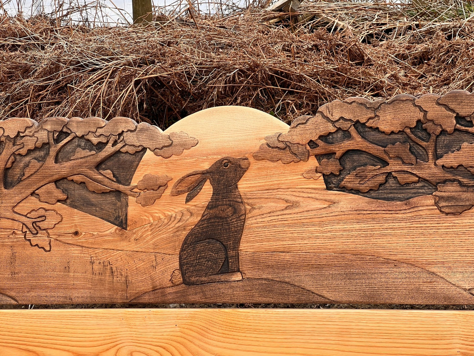 Hand-carved wooden hare in natural woodland setting — detail from handmade oak bed headboard, Wales