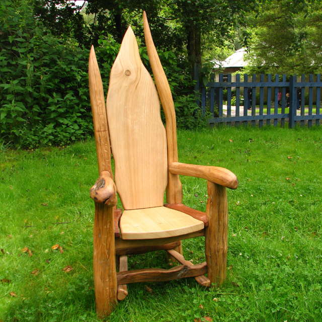 Child sitting in carved hobbit storytelling chair — handmade oak furniture, Wales