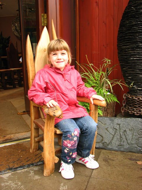 Hobbit storytelling throne chair in garden — carved oak, handmade in Mid Wales
