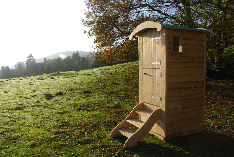 Wooden composting toilet in sunny open field