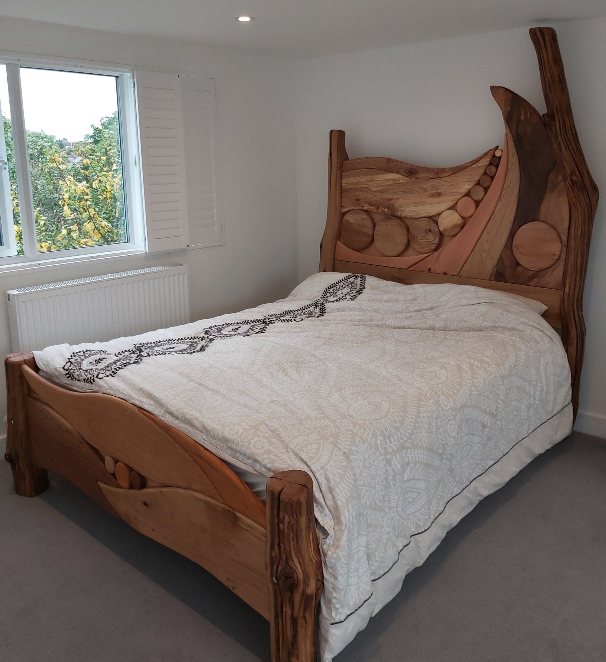 Handmade constellation bed frame with a unique headboard design featuring circular wood details, creating a natural and artistic focal point in Indie’s bedroom