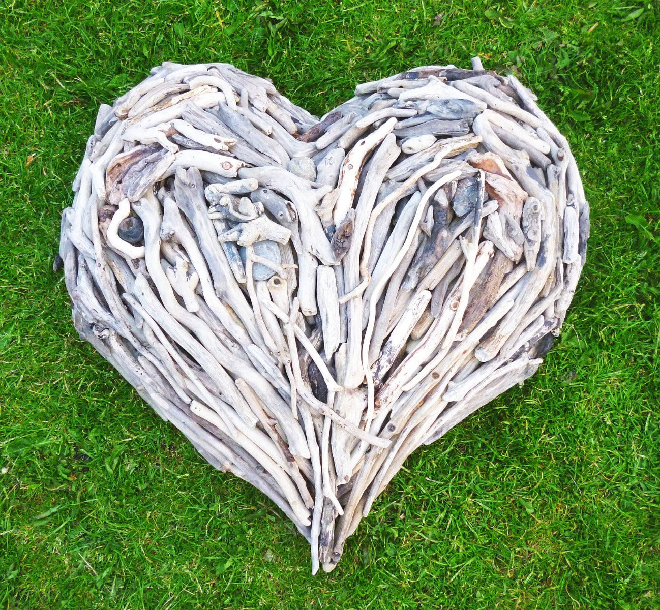 Driftwood heart sculpture on green grass