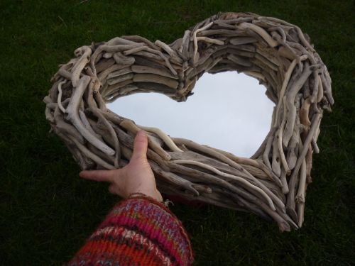 Hand holding heart-shaped driftwood mirror