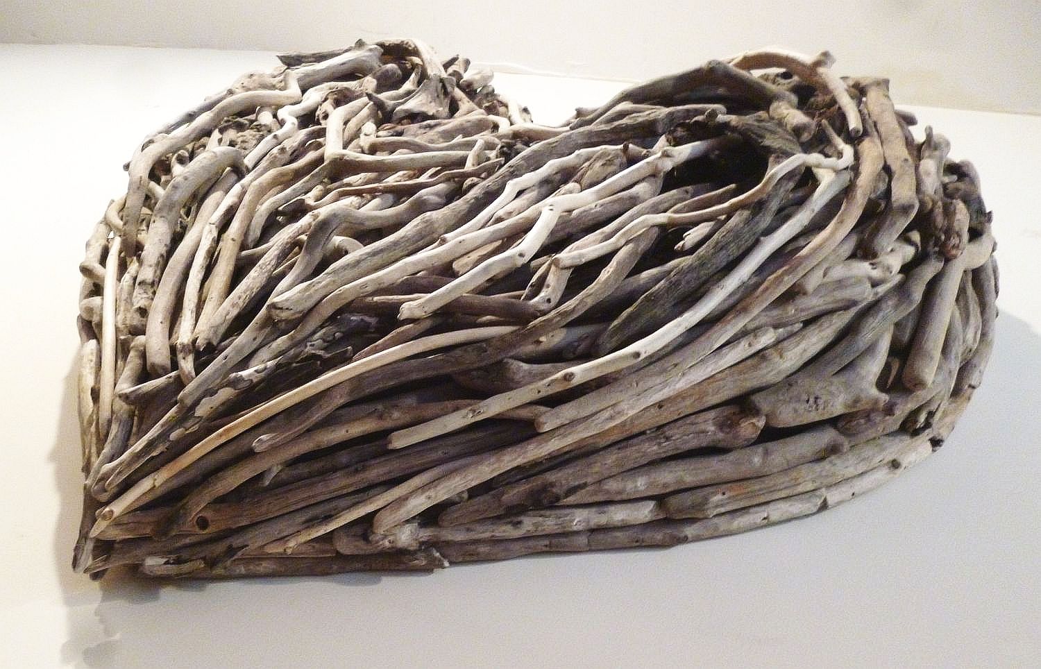 Close-up of driftwood heart sculpture on white surface