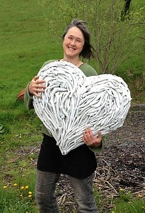 Person holding large white driftwood heart outdoors