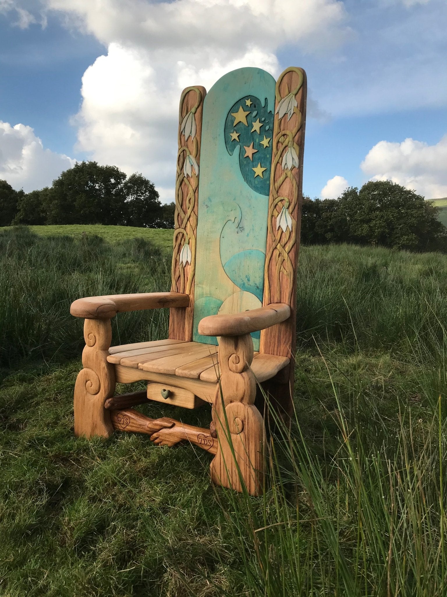 Handmade outdoor literacy chair in lush meadow — carved oak, bespoke, Wales