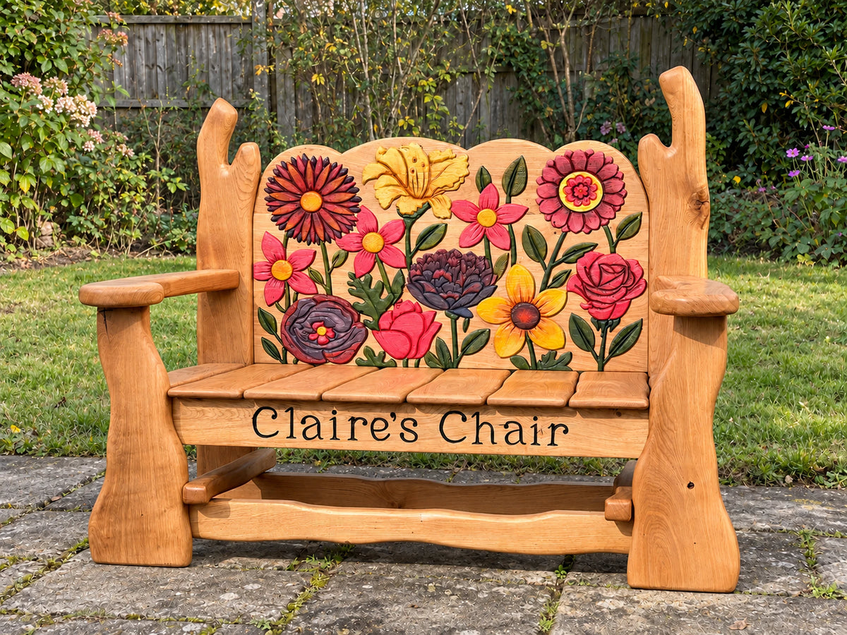 Hand-carved floral memorial bench in oak on a lawn, with the carved name on the front brace