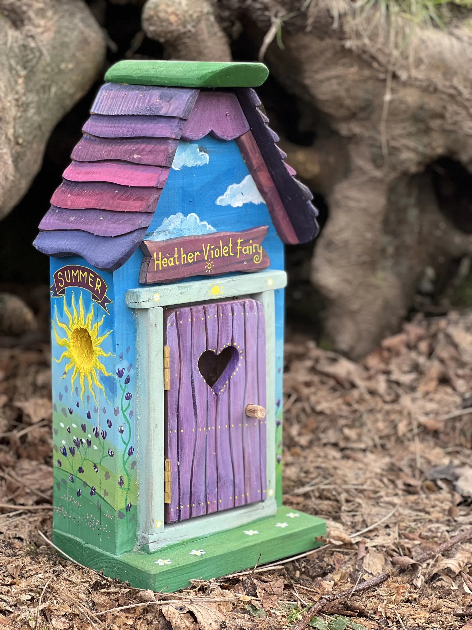 Close-up detail of mini fairy house painted decorations and handcrafted hexagonal timber construction