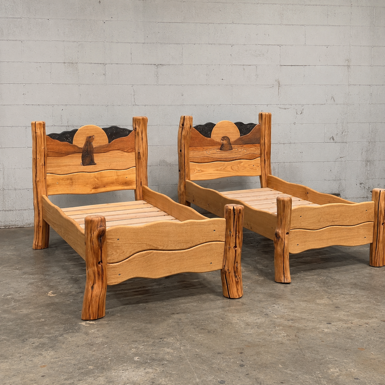 Pair of handmade solid wood single beds with carved hare and seal moonlit headboards in the workshop