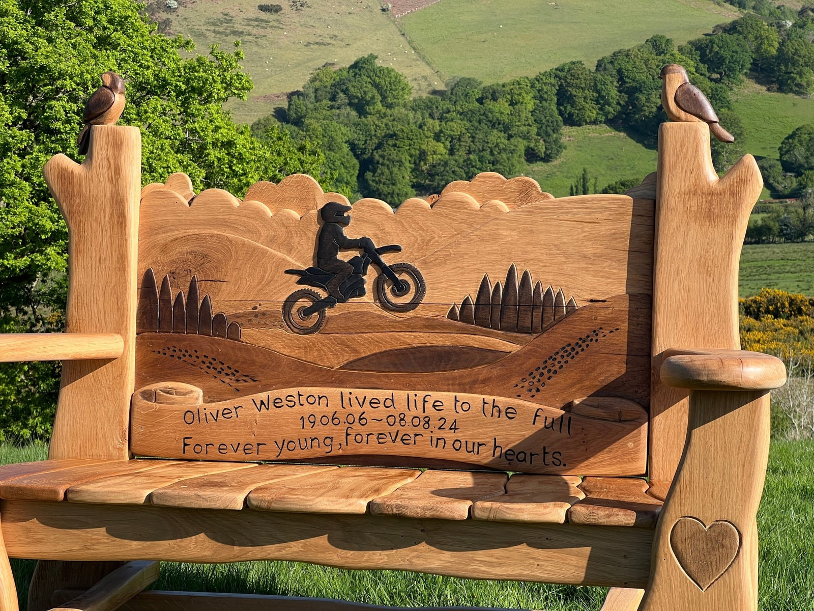 Backrest of handmade oak memorial bench with carved motorbike rider silhouette — bespoke, Wales