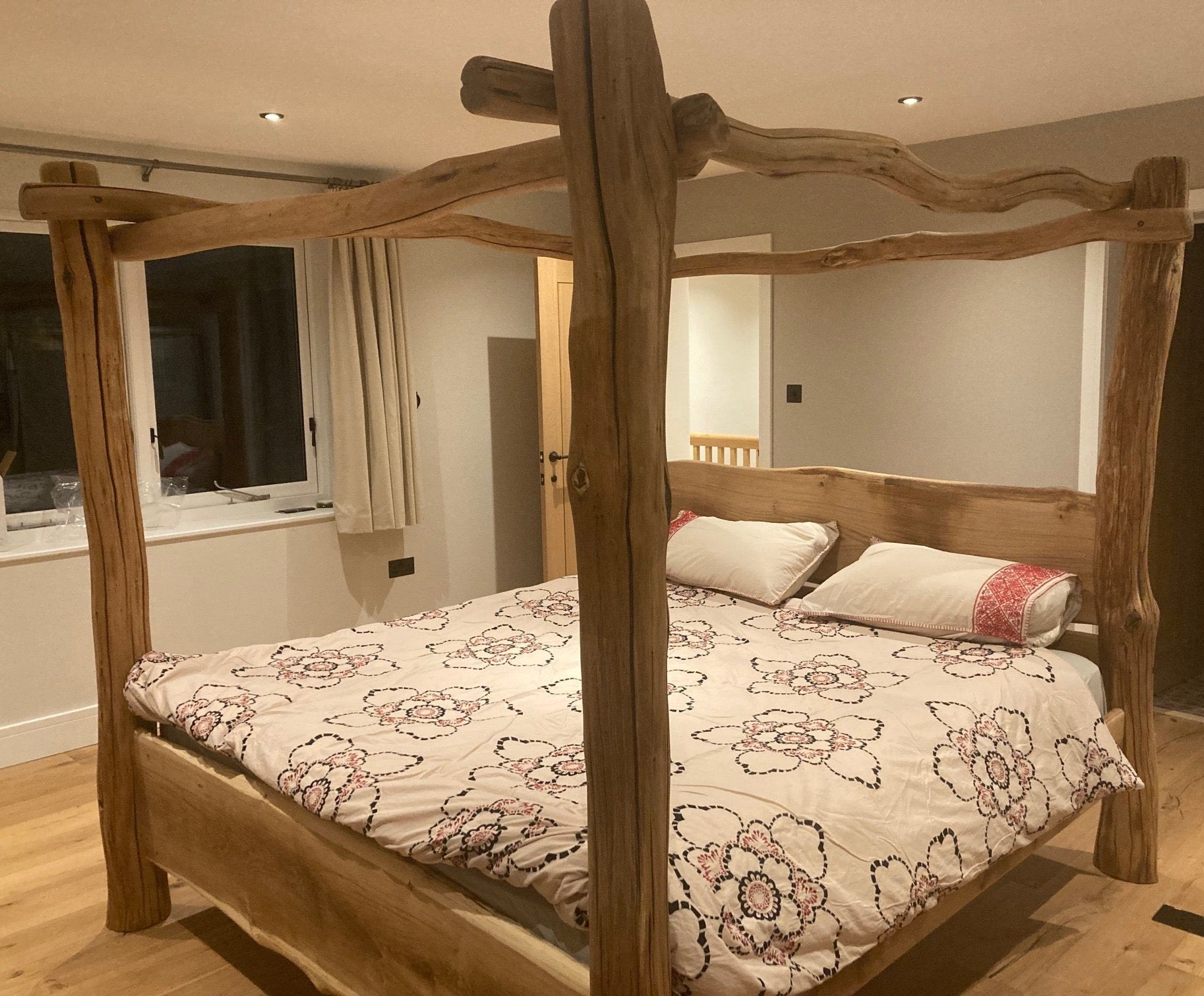 Handcrafted natural wood four-poster bed with rustic design, featuring a unique wood grain pattern, adding warmth and character to Nami’s cozy bedroom