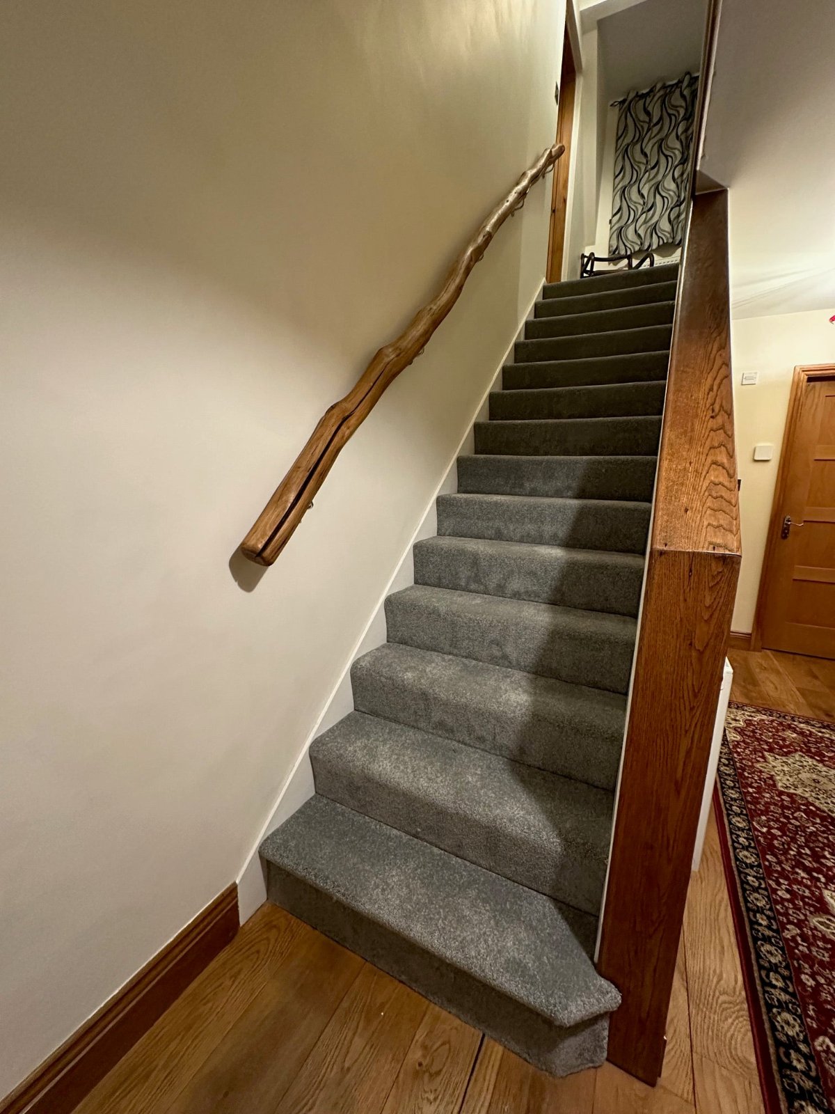 Staircase with a natural branch handrail, securely mounted on the wall with handrail brackets, offering a unique driftwood-style safe handrail design