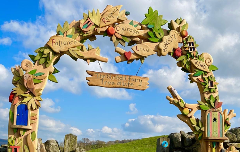 Decorative arch with fairy-themed elements against a blue sky with clouds