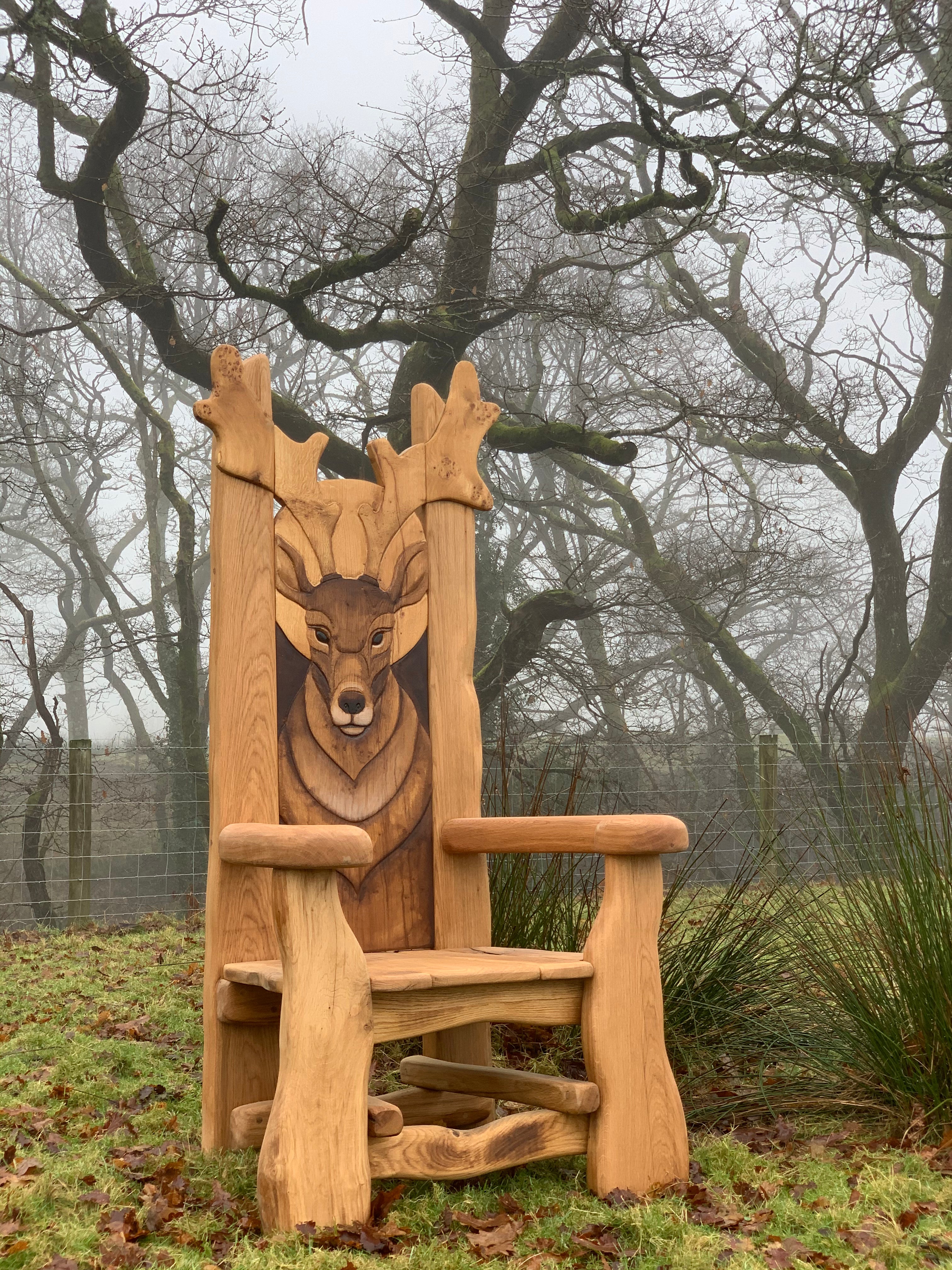 Chaise en bois avec sculpture de cerf dans un paysage brumeux.