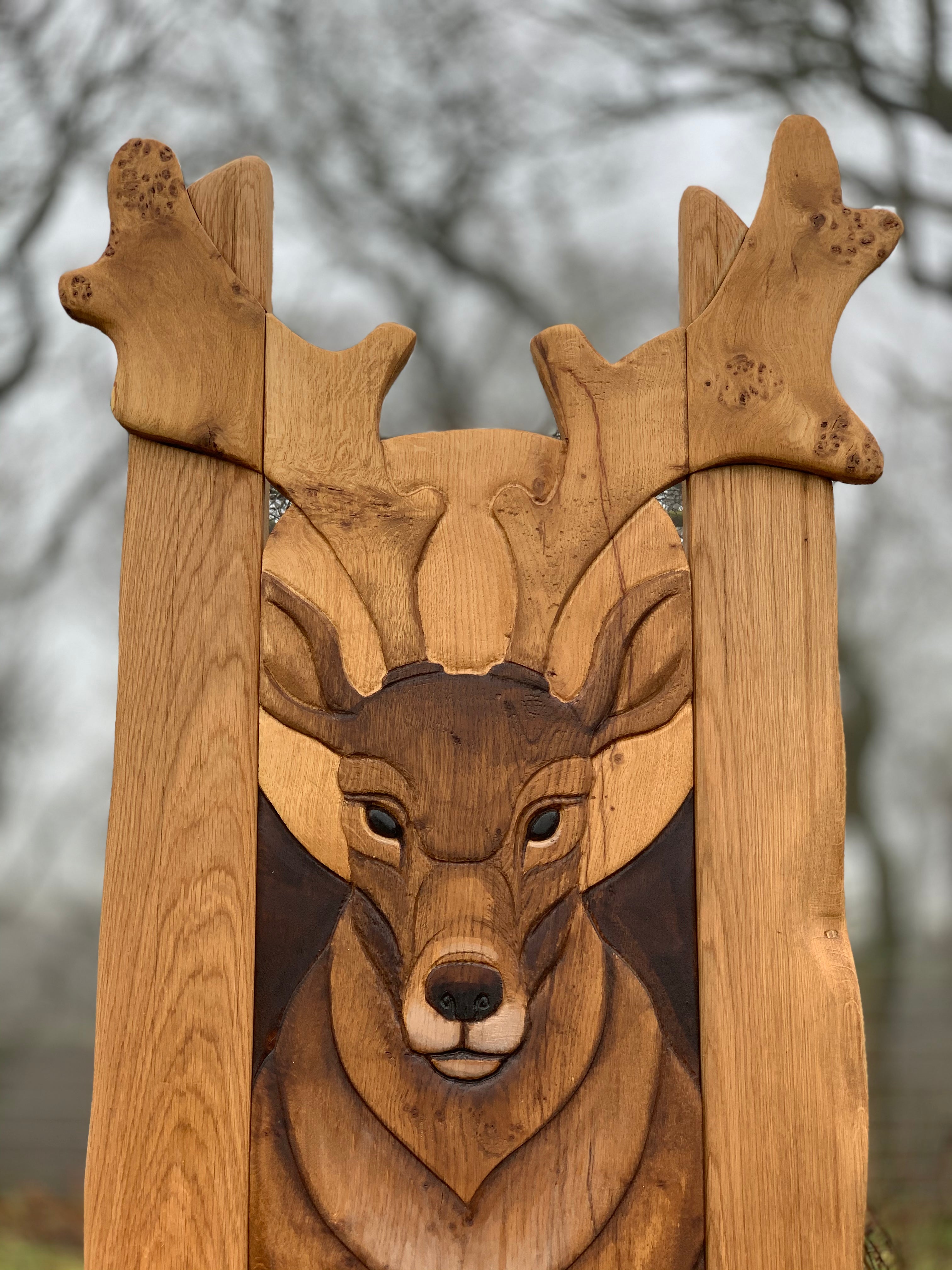 Gros plan d'une sculpture de cerf sur une chaise en bois dans une forêt brumeuse.