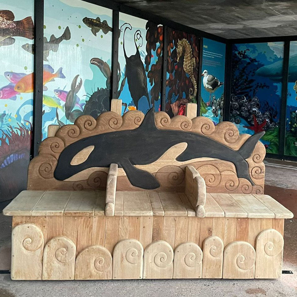 Hand-carved solid oak orca memorial bench front view with wave-carved backrest, Rottingdean seafront