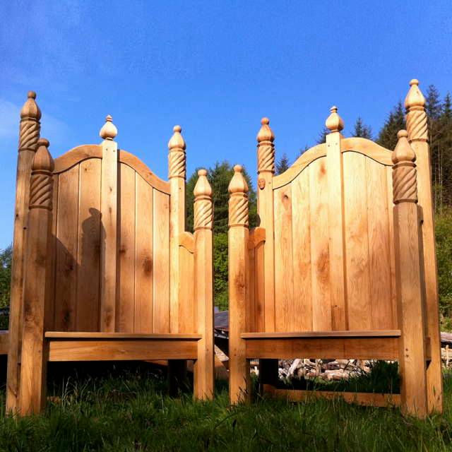 Pair of ornate hand-carved oak storytelling chairs on grass — bespoke, handmade Wales