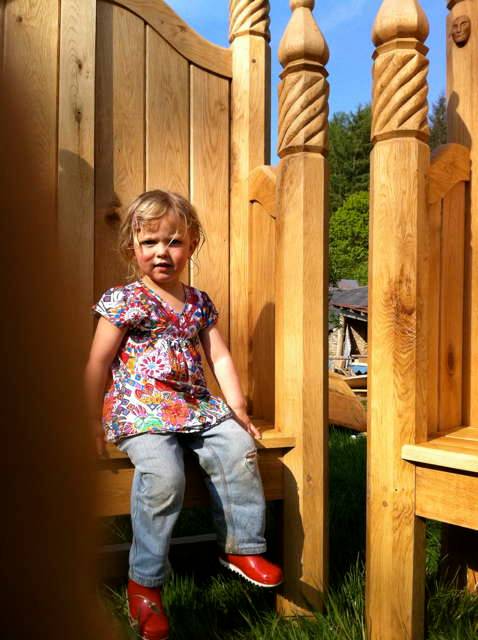 Child sitting on ornate hand-carved oak storytelling chair — bespoke, handmade Wales