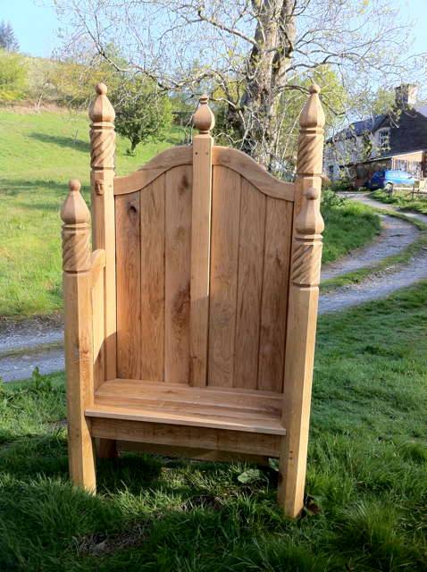 Single ornate hand-carved oak storytelling chair on grassy path — bespoke, Wales