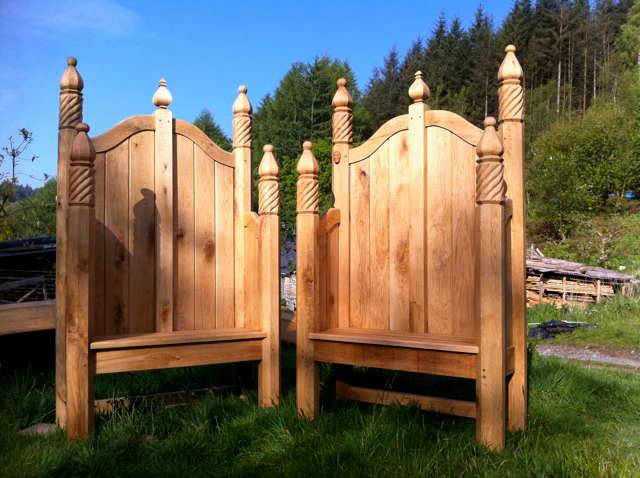 Two ornate hand-carved oak storytelling chairs in garden — bespoke, Wales