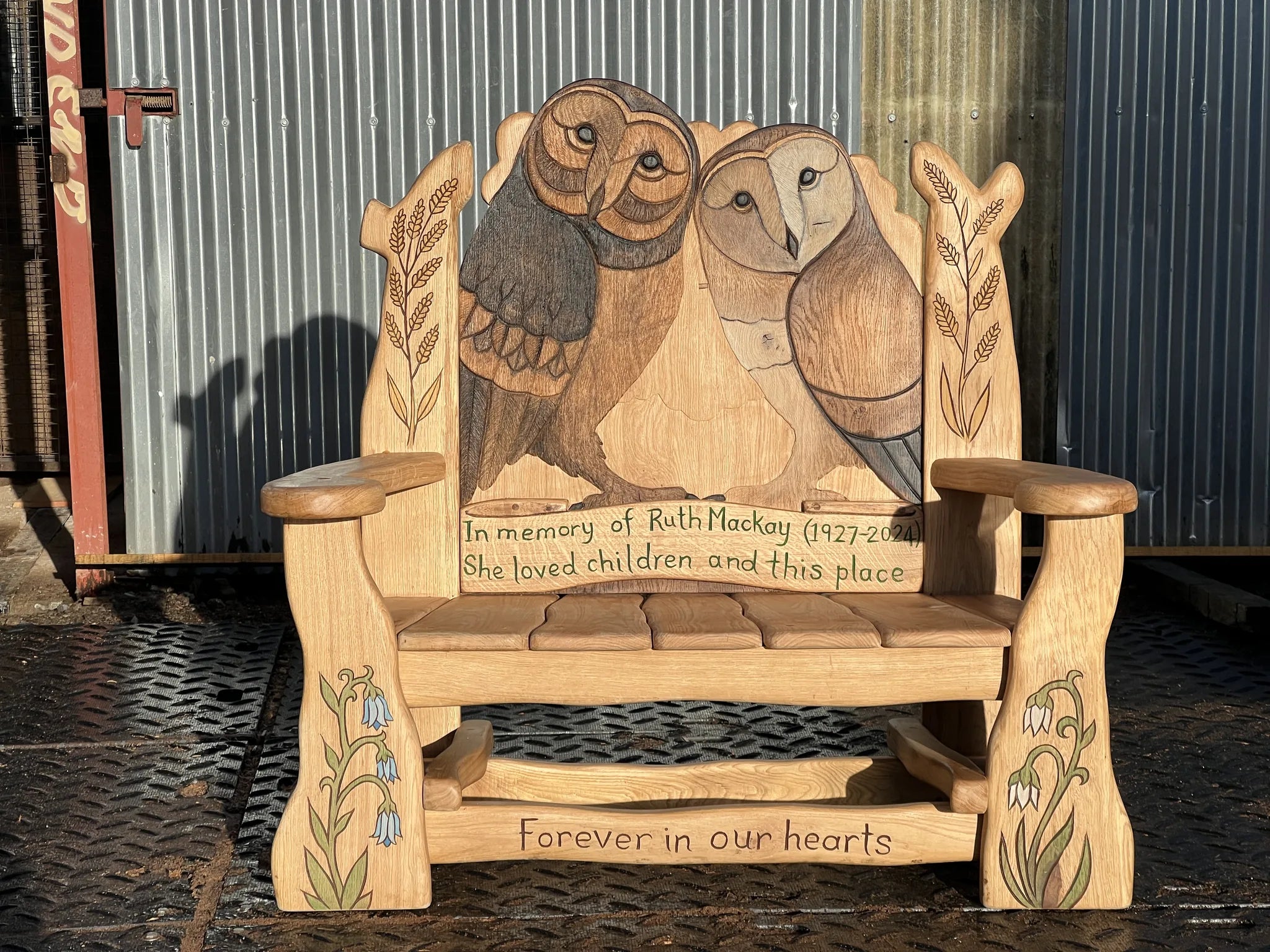Two barn owls hand-carved and painted on solid oak memorial bench backrest with personal inscription and wildflower carvings