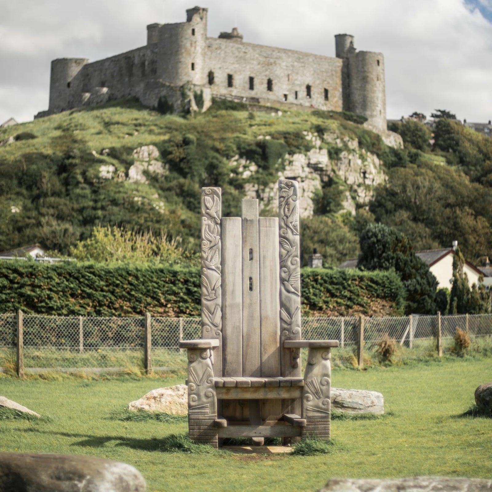 Weathered oak Pen Y Graig storytelling throne at Harlech with Harlech Castle behind | Meirion's Trail Wales