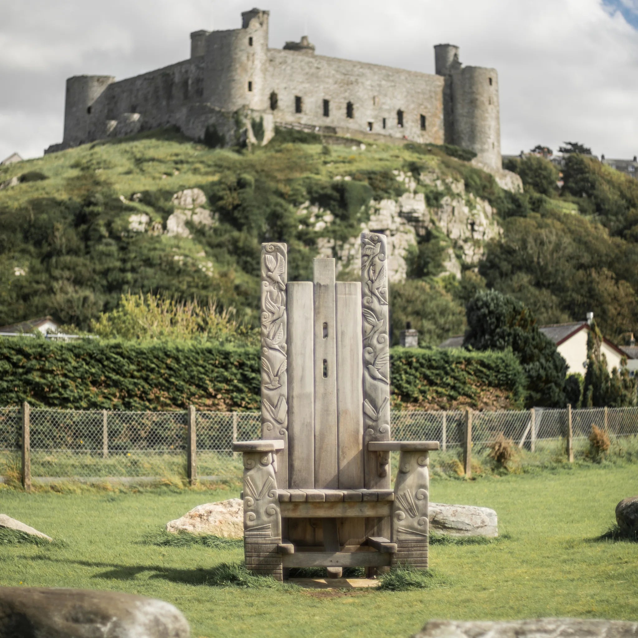 Weathered oak Pen Y Graig storytelling throne at Harlech with Harlech Castle behind | Meirion's Trail Wales