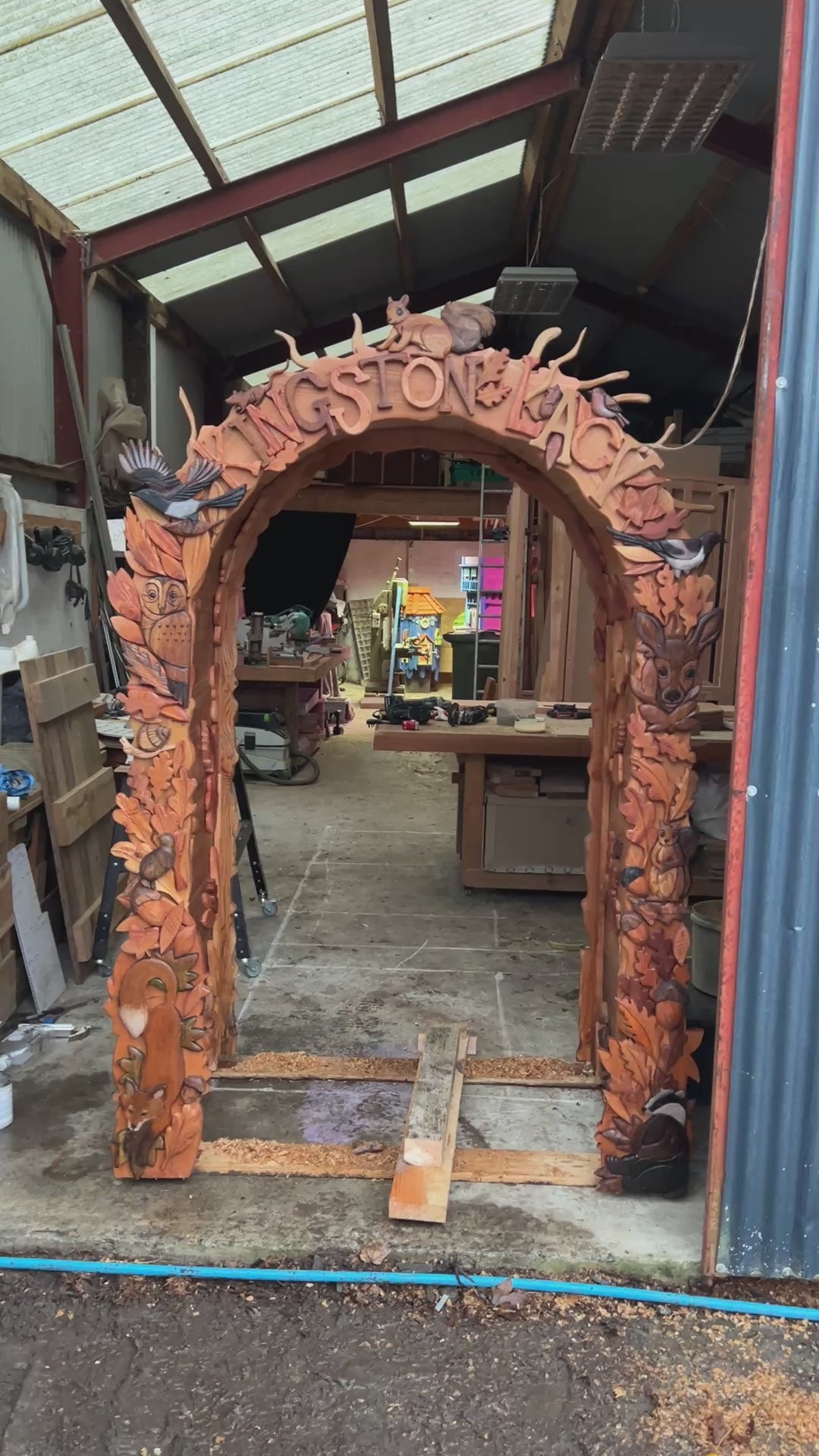 front view of fantasy carved wooden arch with woodland animals owls birds fox and leaves