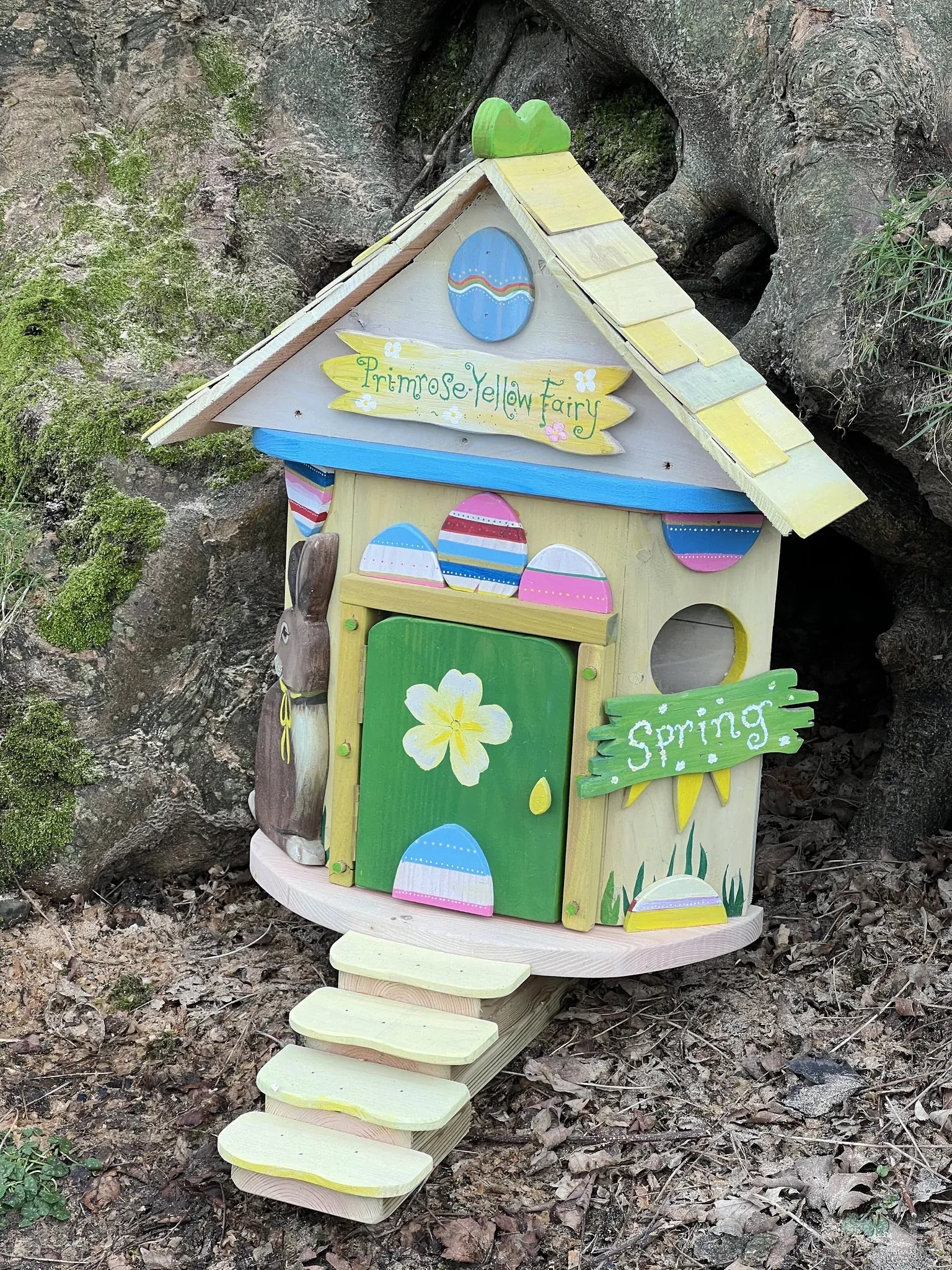 Close-up detail of primrose yellow fairy house door and floral window decorations