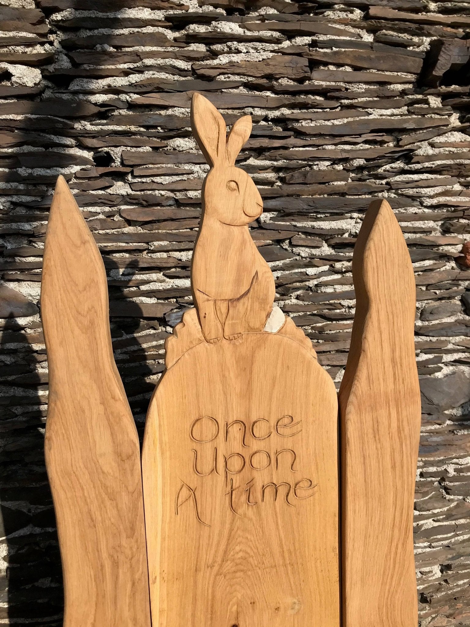 Nahaufnahme eines geschnitzten Kaninchens auf einem Eichenstuhl mit der Aufschrift "Once Upon A Time".