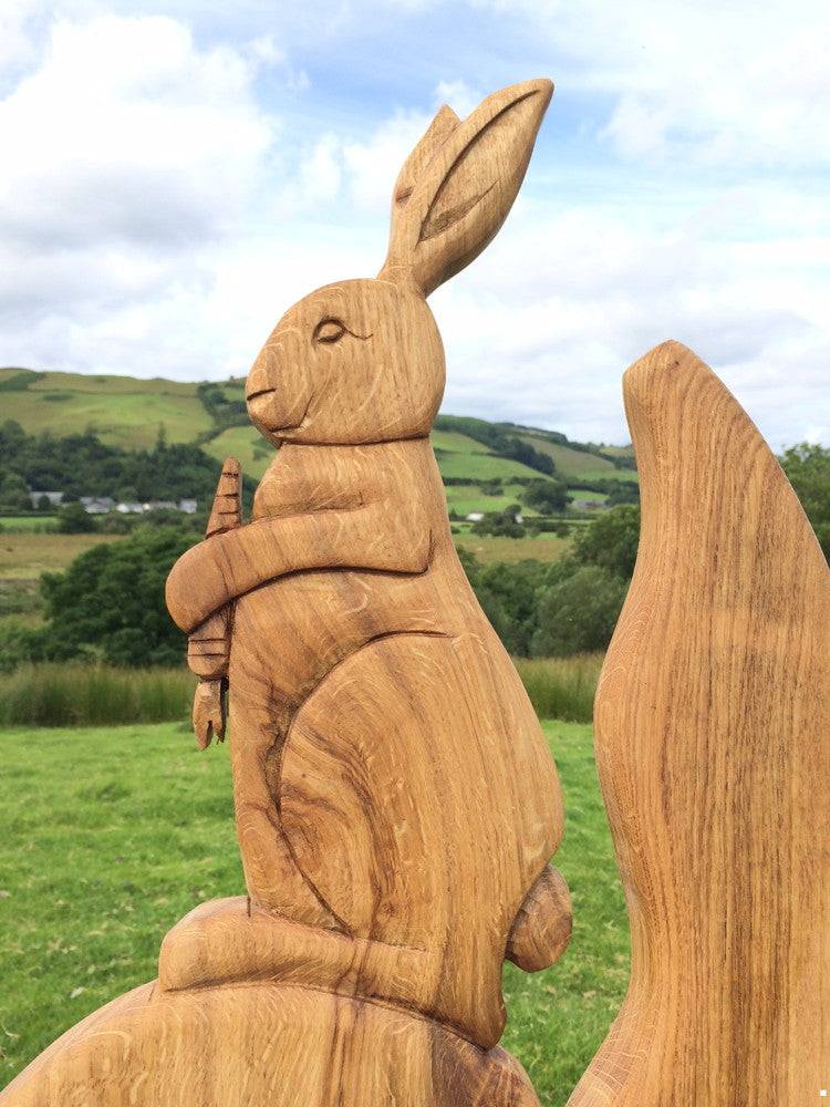 Gros plan d'une sculpture de lapin tenant une carotte sur une chaise en chêne