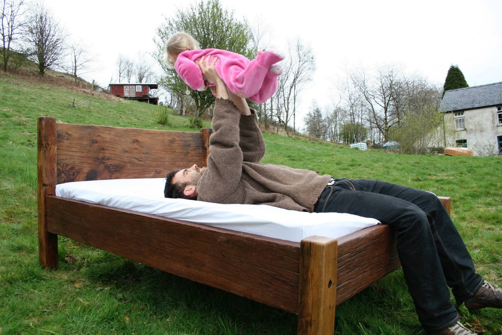Man and child on handmade reclaimed oak bed outdoors — bespoke, Wales