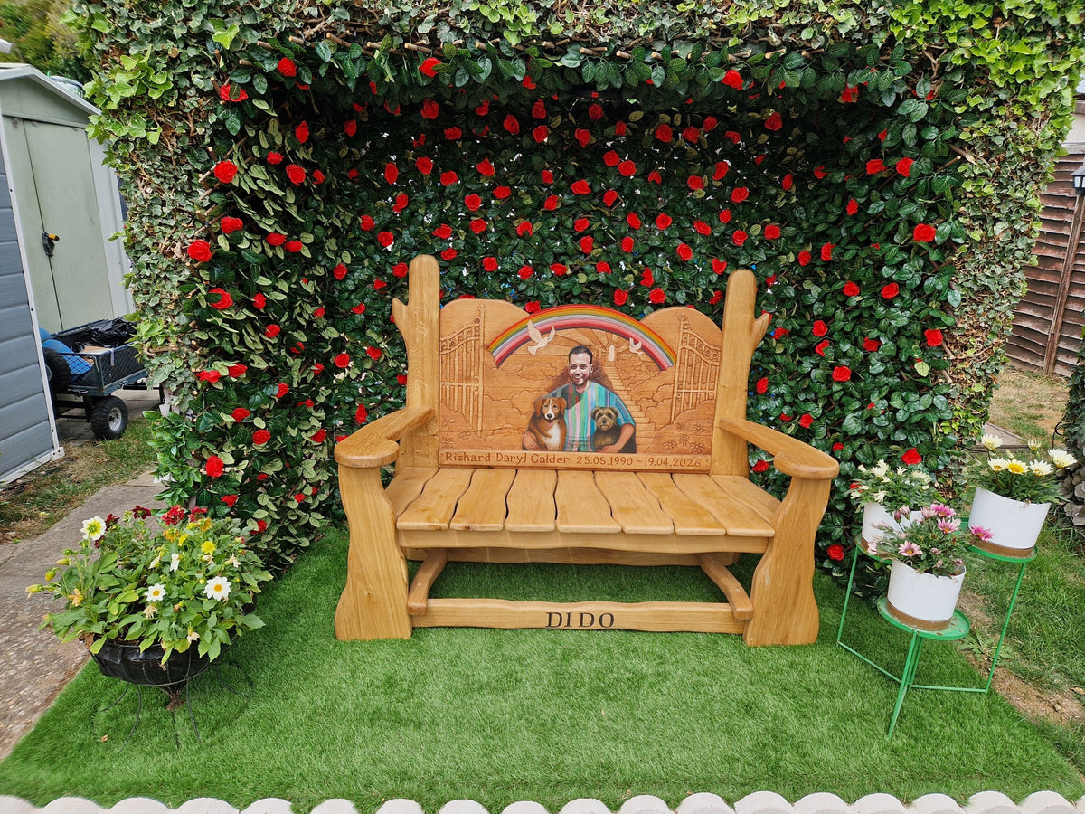 Solid oak memorial bench with hand-painted portrait and carved rainbow, gates and doves, set in a garden rose arbour