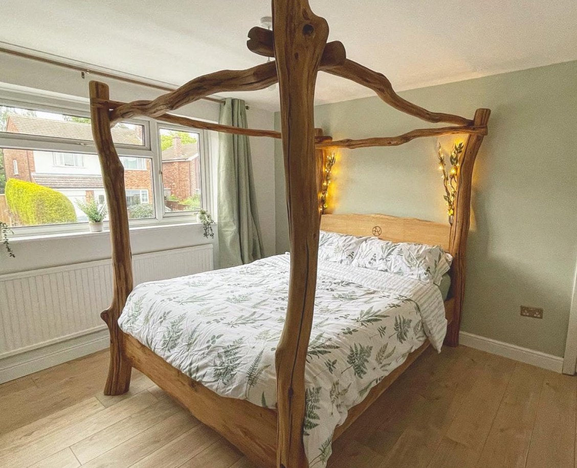 Rustic handcrafted four-poster bed in natural wood with unique live edge frame, styled with botanical bedding and soft lighting in a cozy bedroom setting