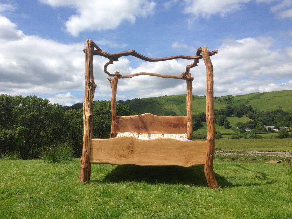 Rustic oak four poster bed in natural setting — handcrafted bedroom furniture, Wales