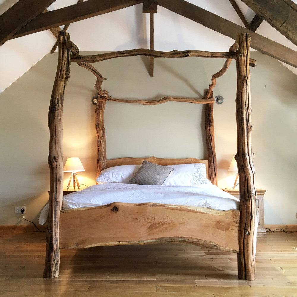 Handmade rustic oak four-poster tree bed featuring organic twists and flowing grain, perfect for adding woodland charm and a natural centerpiece to any bedroom.