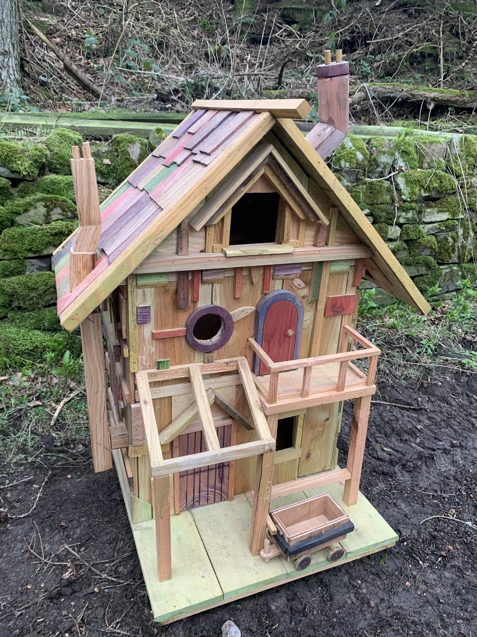 Side view of rustic woodland treehouse showing bark-on branch supports and multi-level platform construction