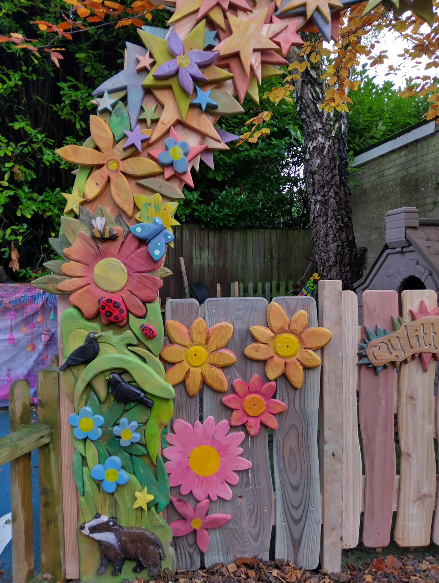 Close-up of colourful carved wooden stars and flowers on the My Little Stars Nursery arch