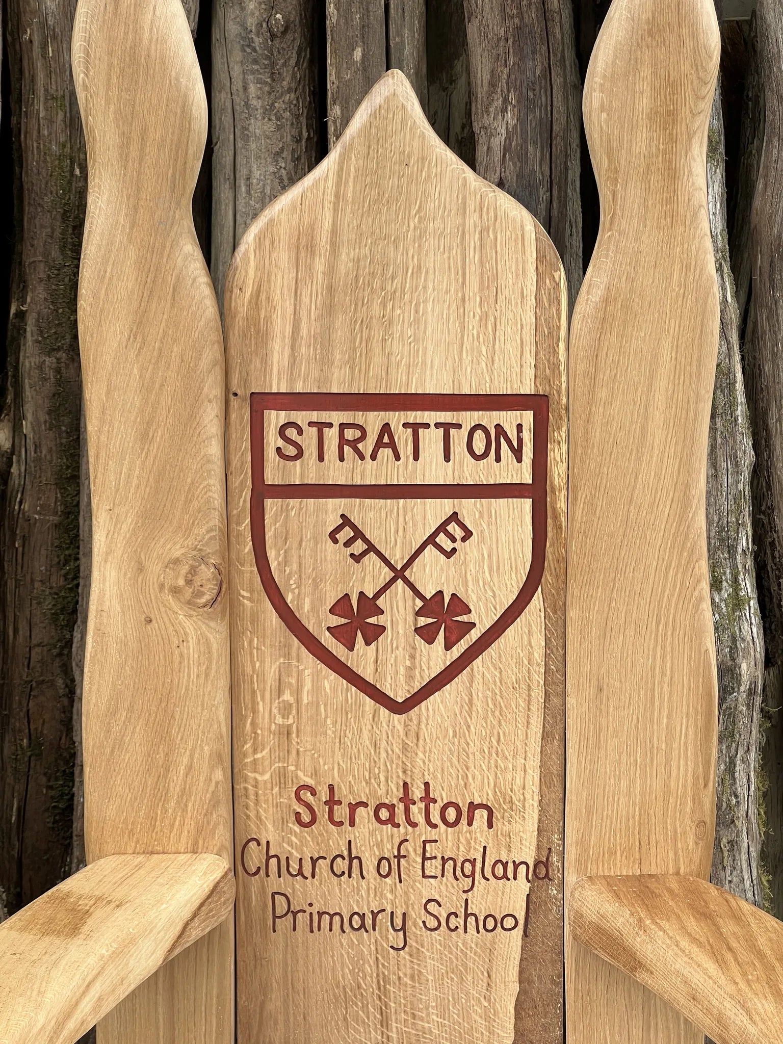 Close-up of the Stratton Church of England Primary School crest carved into a storytelling chair backrest