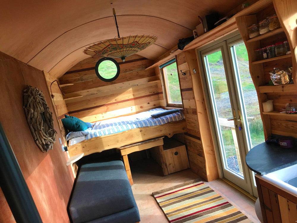 Gemütlicher Innenraum der Schäferhütte mit Bett und Sitzgelegenheiten