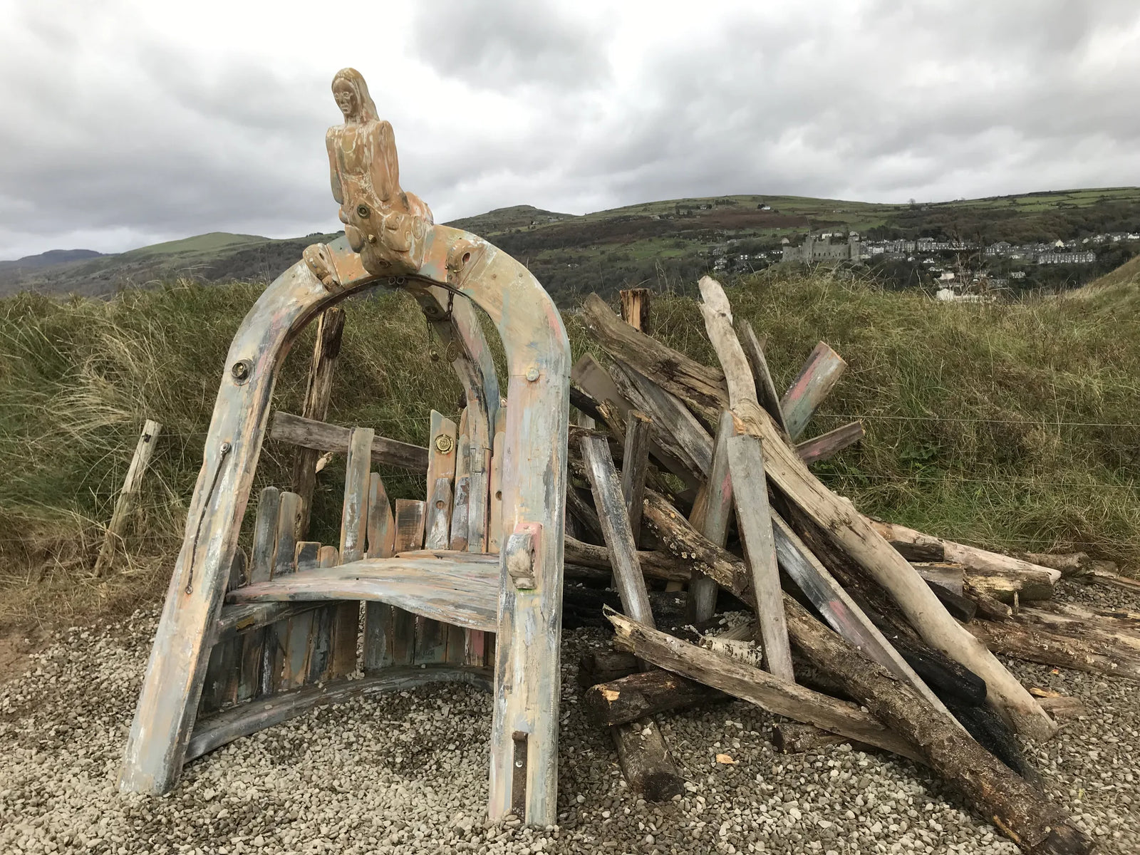 Shipwreck storytelling chair in solid oak with arch and figurehead | Harlech town on hillside in background