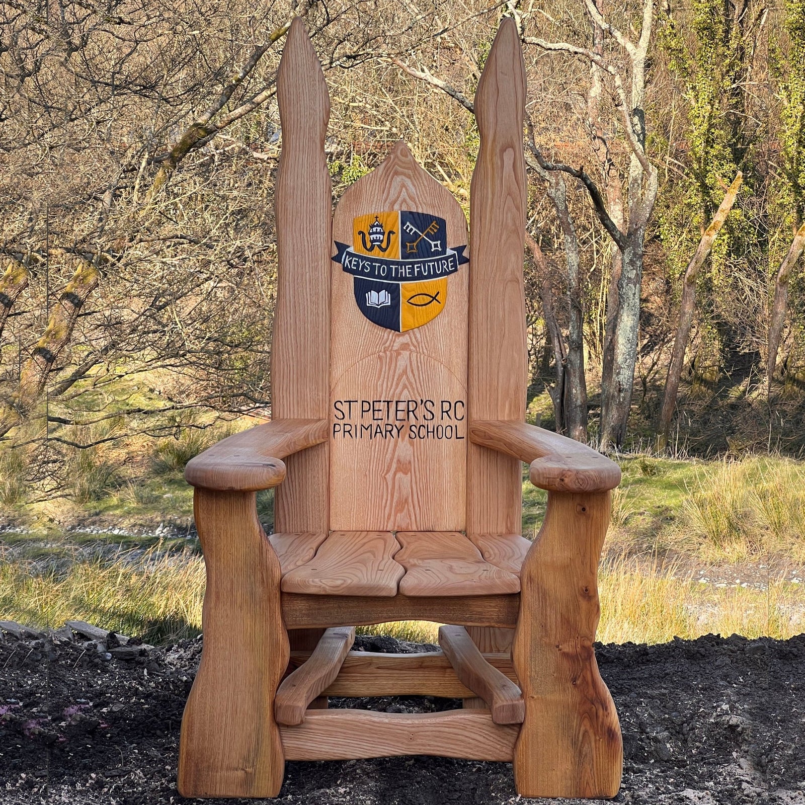 Handcrafted wooden storytelling chair with engraved St Peter’s RC Primary School crest and motto Keys to the Future
